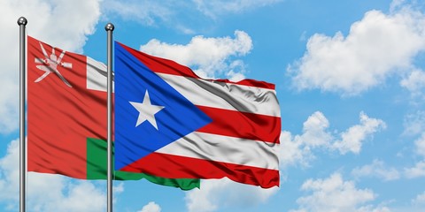 Oman and Puerto Rico flag waving in the wind against white cloudy blue sky together. Diplomacy concept, international relations.