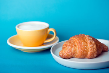 yellow cup with croissant on a blue background