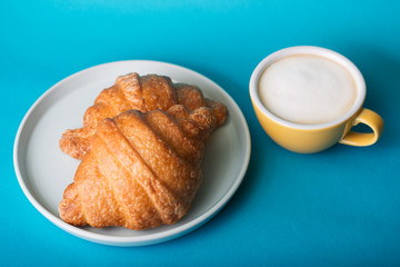 yellow cup with croissant on a blue background