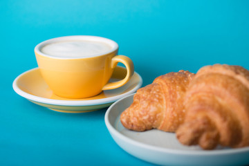 yellow cup with croissant on a blue background