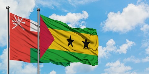 Oman and Sao Tome And Principe flag waving in the wind against white cloudy blue sky together. Diplomacy concept, international relations.