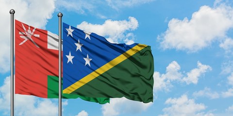 Oman and Solomon Islands flag waving in the wind against white cloudy blue sky together. Diplomacy concept, international relations.