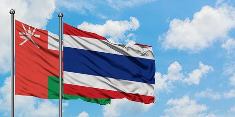 Oman and Thailand flag waving in the wind against white cloudy blue sky together. Diplomacy concept, international relations.