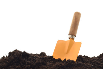 Yellow metal shovel in black soil or substrate by gardening isolated on white