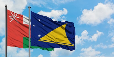 Oman and Tokelau flag waving in the wind against white cloudy blue sky together. Diplomacy concept, international relations.