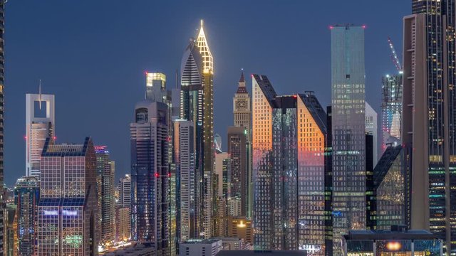 Aerial view to financial district with new towers and tall buildings with busy roads day to night transition timelapse in Dubai Downtown from above with traffic on highway, Dubai, United Arab Emirates