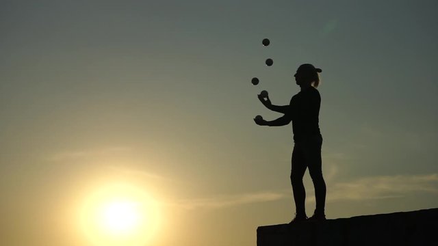Circus artist juggling with balls on colorful sunset