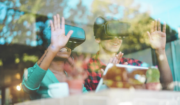 Young students using virtual reality goggles in modern coworking bar - Window reflection view - Millennials people having fun with vr technology - Future and digital concept - Focus on girl headset