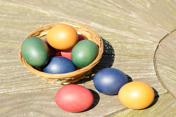 colorful easter eggs eggs in the basket standing on wooden table in the garden