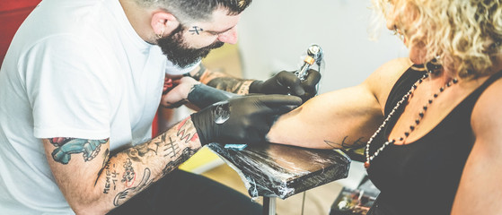 Young tattoo artist working in his ink creative studio - Tattoist at work - Contemporary skin trends - Focus on man right hand, glove