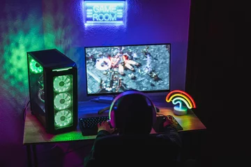 Fotobehang Gaming Young gamer playing at strategy online game - Male guy having fun gaming and streaming online - New technology game trends and entertainment concept - Soft focus on his right hand  © DisobeyArt