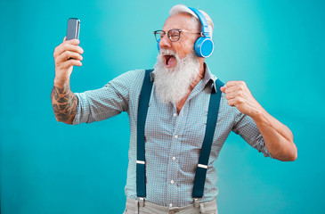 Senior hipster man using smartphone app for creating playlist with rock music - Trendy tattoo guy...