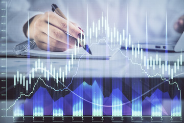 Double exposure of woman's hands making notes with forex graph hologram. Concept technical analysis.