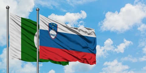 Pakistan and Slovenia flag waving in the wind against white cloudy blue sky together. Diplomacy concept, international relations.