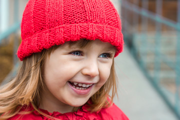 emotional portrait, face of a little girl in red clothes closeup laughing joyfully, happy childhood, space for text