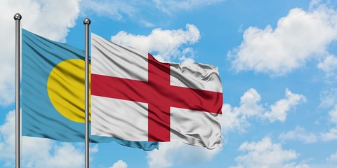 Palau and England flag waving in the wind against white cloudy blue sky together. Diplomacy concept, international relations.