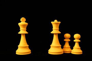 White King and Queen with pawns as divorce and separation concept. Standard chess wooden pieces on black background