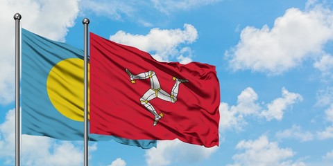 Palau and Isle Of Man flag waving in the wind against white cloudy blue sky together. Diplomacy concept, international relations.