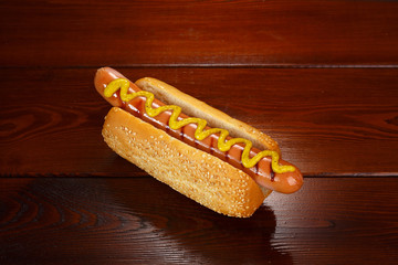 Classic hot dog with mustard on a background of wooden boards.