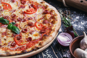 Pizza with sausages, ham, onions and tomatoes
