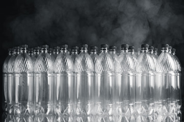 empty plastic bottles on black background with smoke, pollution concept