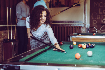 Fototapeta premium Beautiful smiling women playing billiards at a bar