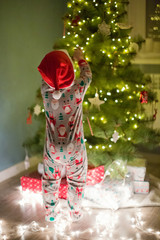 happy little boy in pyjamas decorate Christmas tree