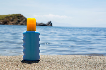 Suntan cream on sandy beach on sunny day at the blue sea background. Relaxation concept.