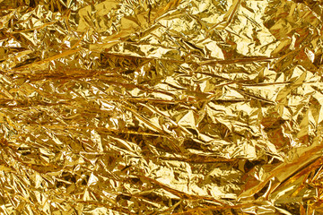 Gold leaf background texture with shiny crumpled uneven surface
