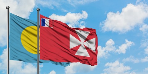 Palau and Wallis And Futuna flag waving in the wind against white cloudy blue sky together. Diplomacy concept, international relations.