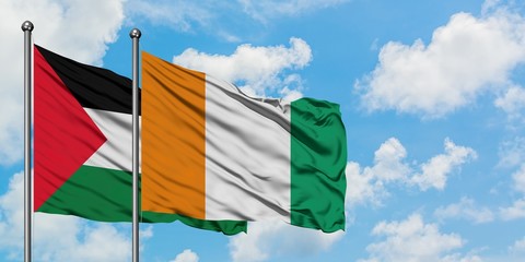 Palestine and Cote D'Ivoire flag waving in the wind against white cloudy blue sky together....