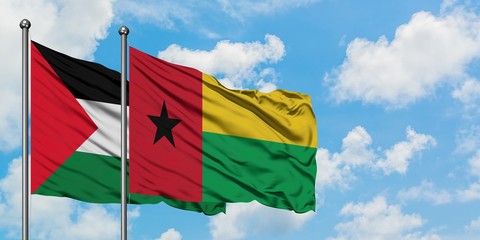 Palestine and Guinea Bissau flag waving in the wind against white cloudy blue sky together. Diplomacy concept, international relations.