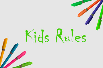 Colored markers on a white background, accompanied by the words kids rules and with a fun design