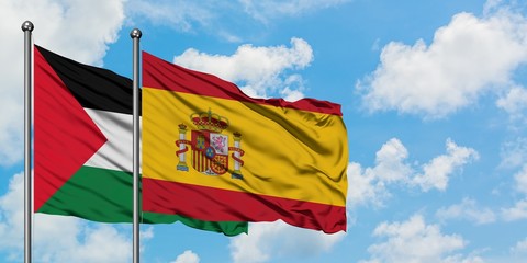 Palestine and Spain flag waving in the wind against white cloudy blue sky together. Diplomacy concept, international relations.