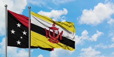 Papua New Guinea and Brunei flag waving in the wind against white cloudy blue sky together. Diplomacy concept, international relations.