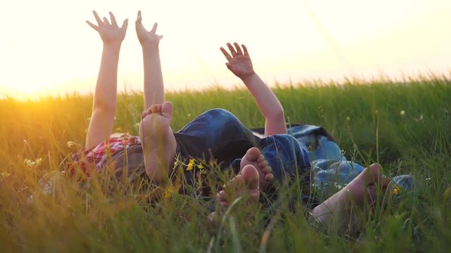 happy family kids concept. children with bare feet lie on the grass in the park on the lawn have a rest play have fun. brother and sister friendship bare feet relax on grass outdoors. little boy and