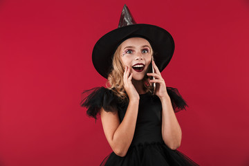 Cheerful little girl wearing Halloween witch costume