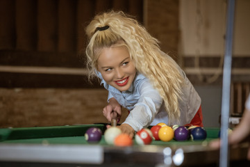 Beautiful smiling women playing billiards at a bar