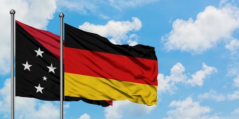 Papua New Guinea and Germany flag waving in the wind against white cloudy blue sky together. Diplomacy concept, international relations.