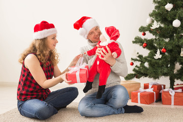 Fototapeta premium Happy couple with baby celebrating Christmas together at home.