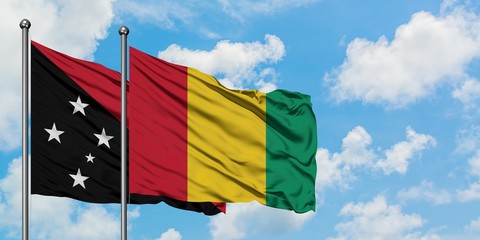 Papua New Guinea and Guinea flag waving in the wind against white cloudy blue sky together. Diplomacy concept, international relations.