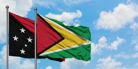 Papua New Guinea and Guyana flag waving in the wind against white cloudy blue sky together. Diplomacy concept, international relations.