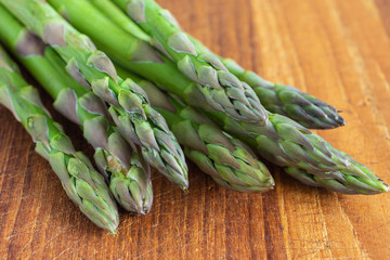 Macro close-up of green asparagus on used kitchen board, horizontally with copy space