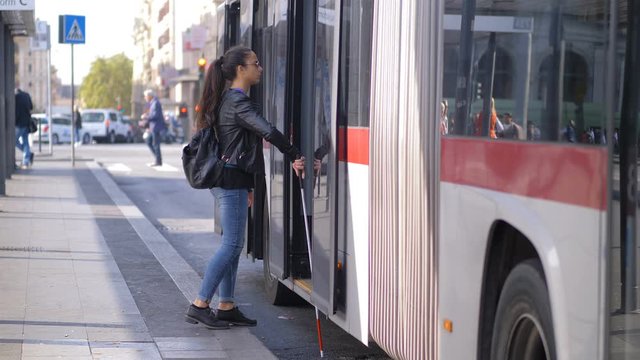 Young blind woman with her stick getting on bus.Transportation,autonomy,blindnes