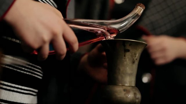 Red liquid is poured from an unusual glass vessel