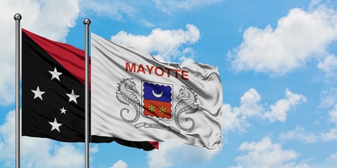 Papua New Guinea and Mayotte flag waving in the wind against white cloudy blue sky together. Diplomacy concept, international relations.