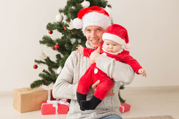 Obraz na płótnie Canvas Father with his baby boy wearing Santa hats celebrating Christmas.