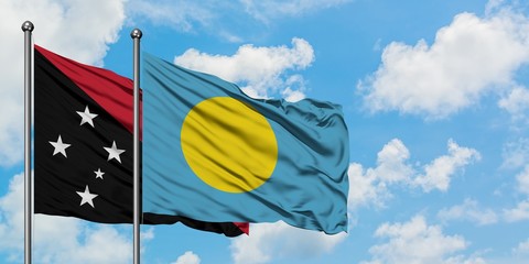 Papua New Guinea and Palau flag waving in the wind against white cloudy blue sky together. Diplomacy concept, international relations.