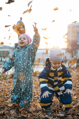 Fototapeta na wymiar Little lovely boy and girl on a walk, emotional portrait, a happy kid walking on an autumn day, autumn leaves under his feet on a sunny day