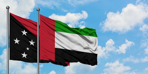Papua New Guinea and United Arab Emirates flag waving in the wind against white cloudy blue sky together. Diplomacy concept, international relations.